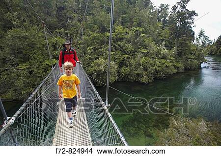 Picture - Family Walking the Abel Tasman Coastal Track at Falls River Suspension Bridge, Abel Tasman National Park, Nelson Region, New Zealand,. Fotosearch