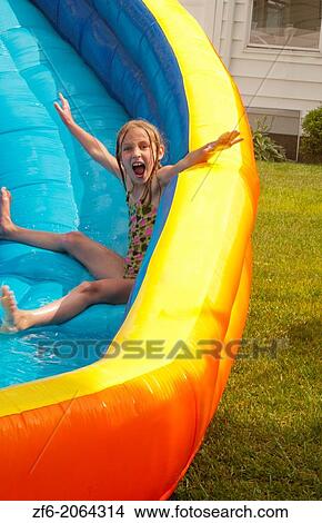 family water slide in back yard at home with water in summer girl age 7 having fun in water and splash. View Large Photo Image Picture - family water slide in back yard at home with water in summer girl age 7 having fun in water and splash.. Fotosearch