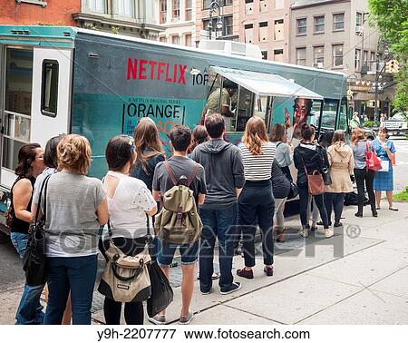 Stock Photo - Fans of the Netflix series??Orange is the New Black?? line up at a rebranded food truck in Soho in New York for free??Crazy Pyes?? and chocolate and vanilla swirl soft ice cream.. Fotosearch