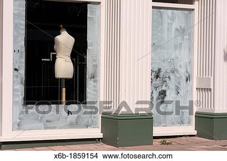 Picture - Fashion mannequin seen through whitewashed windows of an out of business closed shop.. Fotosearch
