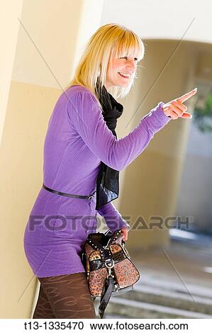 Stock Image - Fashionable young woman is pointing at someone with her forefinger. Fotosearch