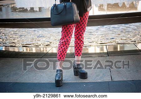Stock Image - Fashionistas arrive and pose in their finery outside of the Fall 2014 Fashion Week shows in Lincoln Center in New York. This year some designers are abandoning the tents at Lincoln Center to hold their shows at far flung venues, including Brooklyn.. Fotosearch