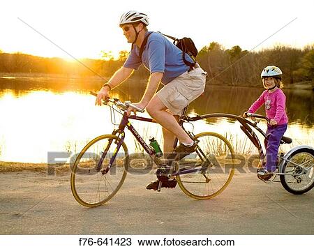 Stock Image - Father and daughter riding? tandem? bicycle.. Fotosearch