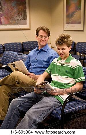 Father and his 15 year old son sitting in waiting room of doctor's office View Large Photo Image Picture - Father and his 15 year old son sitting in waiting room of doctor's office. Fotosearch