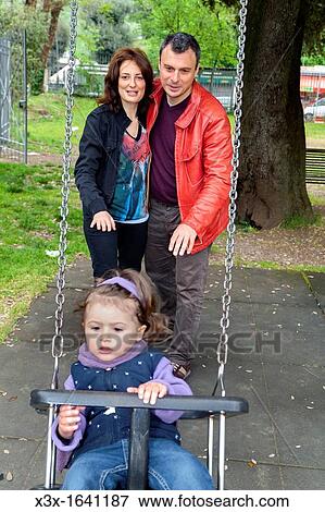 Father and mother pushing daughter on a swing View Large Photo Image Stock Photo - Father and mother pushing daughter on a swing. Fotosearch