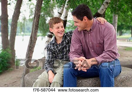 Picture - Father and son embracing while talking,. Fotosearch