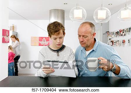 Father and son using tablet computer at home View Large Photo Image Picture - Father and son using tablet computer at home. Fotosearch