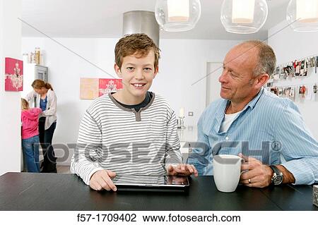 Father and son using tablet computer at home View Large Photo Image Stock Image - Father and son using tablet computer at home. Fotosearch