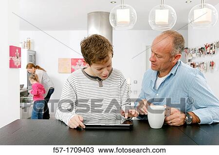 Father and son using tablet computer at home View Large Photo Image Stock Image - Father and son using tablet computer at home. Fotosearch