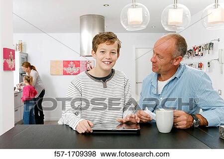 Stock Photo - Father and son using tablet computer at home. Fotosearch
