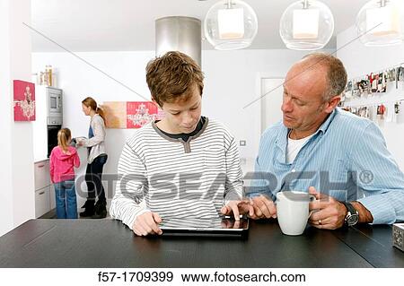 Father and son using tablet computer at home View Large Photo Image Stock Photo - Father and son using tablet computer at home. Fotosearch