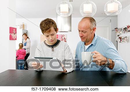 Father and son using tablet computer at home View Large Photo Image Stock Photo - Father and son using tablet computer at home. Fotosearch