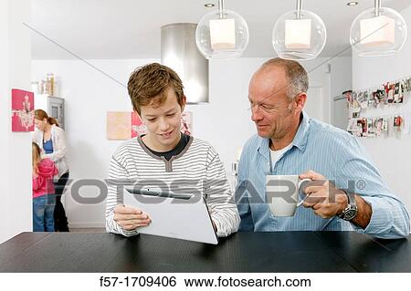 Father and son using tablet computer at home View Large Photo Image Stock Photograph - Father and son using tablet computer at home. Fotosearch