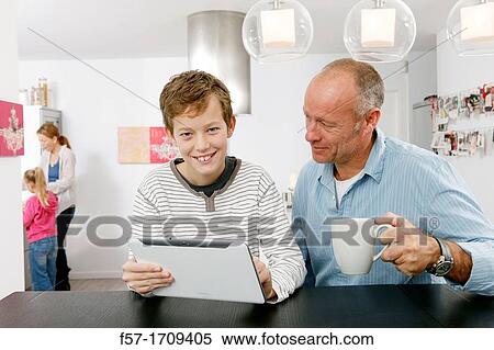 Father and son using tablet computer at home View Large Photo Image Stock Photography - Father and son using tablet computer at home. Fotosearch