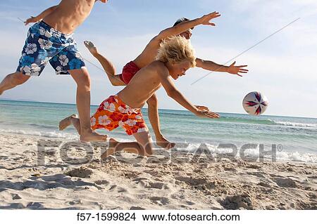 Father and sons playing ball on the beach View Large Photo Image Picture - Father and sons playing ball on the beach. Fotosearch