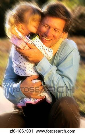 Father gets a great hug from his daughter after getting a surprise gift in the sunshine outdoors with love View Large Photo Image Stock Image - Father gets a great hug from his daughter after getting a surprise gift in the sunshine outdoors with love. Fotosearch