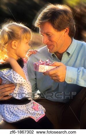 Father gets a great hug from his daughter after getting a surprise gift in the sunshine outdoors with love View Large Photo Image Stock Image - Father gets a great hug from his daughter after getting a surprise gift in the sunshine outdoors with love. Fotosearch