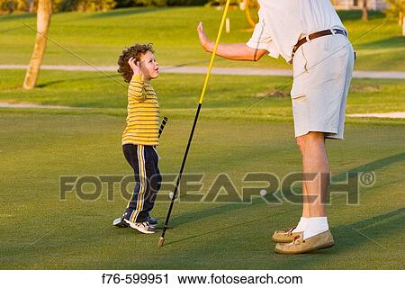 Stock Image - Father gives son? high five? while golfing. Miami. Florida. USA.. Fotosearch