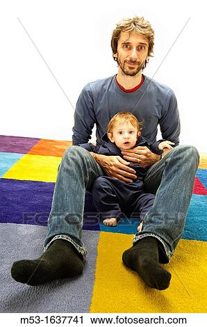 Father hold his 10 months old baby while on a multi coloured carpet View Large Photo Image Stock Image - Father hold his 10 months old baby while on a multi coloured carpet. Fotosearch