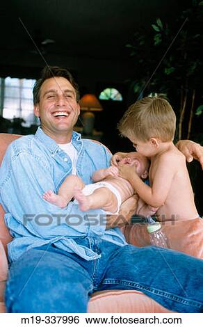 Stock Photograph - Father holding baby and brother playing with him. Fotosearch