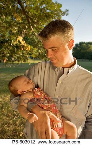 Stock Image - Father holding his infant daughter.. Fotosearch