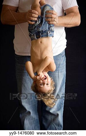 Stock Image - Father holding son upside down - Fort Lauderdale, Florida USA. Fotosearch