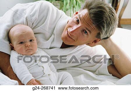 Stock Image - Father in bathrobe with newborn baby (2 months). Fotosearch