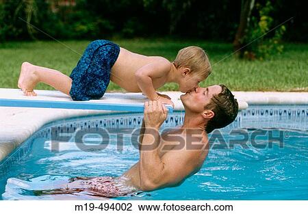 Stock Image - father kissing his son in a pool. Fotosearch