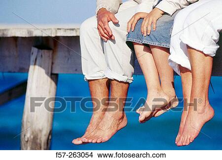 Father, mother and child sitting down in a wooden footbridge over the sea View Large Photo Image Picture - Father, mother and child sitting down in a wooden footbridge over the sea. Fotosearch