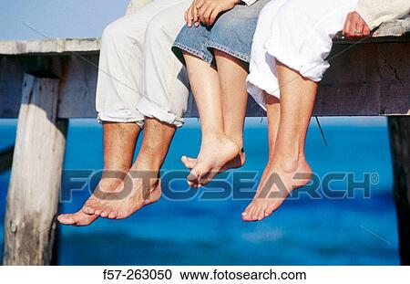 Father, mother and child sitting down in a wooden footbridge over the sea View Large Photo Image Stock Image - Father, mother and child sitting down in a wooden footbridge over the sea. Fotosearch