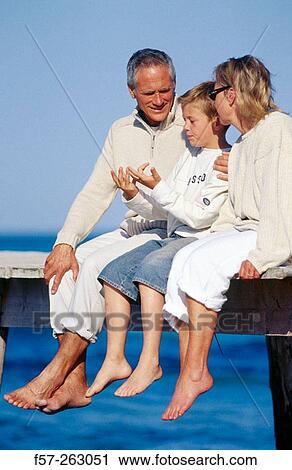 Father, mother and child sitting down in a wooden footbridge over the sea View Large Photo Image Stock Image - Father, mother and child sitting down in a wooden footbridge over the sea. Fotosearch