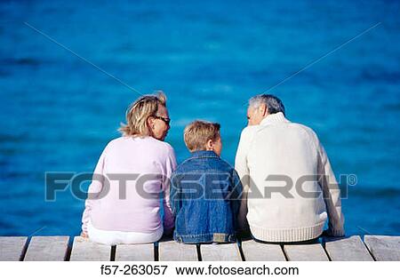Father, mother and child sitting down in a wooden footbridge over the sea View Large Photo Image Stock Photo - Father, mother and child sitting down in a wooden footbridge over the sea. Fotosearch