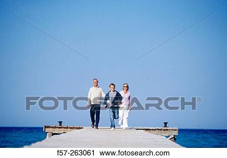 Father, mother and child walking in a wooden footbridge over the sea View Large Photo Image Stock Image - Father, mother and child walking in a wooden footbridge over the sea. Fotosearch