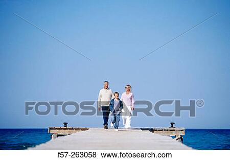Father, mother and child walking in a wooden footbridge over the sea View Large Photo Image Stock Photo - Father, mother and child walking in a wooden footbridge over the sea. Fotosearch