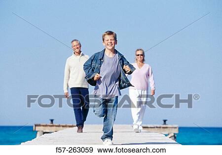Father, mother and child walking in a wooden footbridge over the sea View Large Photo Image Stock Photo - Father, mother and child walking in a wooden footbridge over the sea. Fotosearch