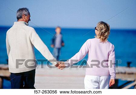 Father, mother and child walking in a wooden footbridge over the sea View Large Photo Image Stock Photograph - Father, mother and child walking in a wooden footbridge over the sea. Fotosearch