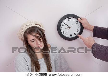 Stock Photograph - Father pointing to a clock next to his teen daughter. Fotosearch