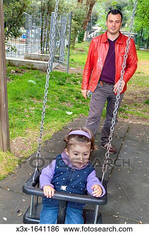 Father pushing daughter on a swing View Large Photo Image Stock Photograph - Father pushing daughter on a swing. Fotosearch