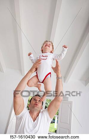 Stock Image - Father throwing his one year old son in the air. Fotosearch