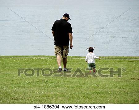 Father walking toward the sea with little daughter beside him View Large Photo Image Picture - Father walking toward the sea with little daughter beside him. Fotosearch
