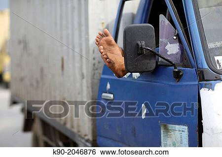 Stock Photograph - Feet hanging out of the window of a truck, Jakarta, Java, Indonesia, Southeast Asia.. Fotosearch