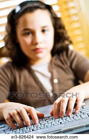 Female caucasian brunette child working on a laptop computer sitting at a table View Large Photo Image Picture - Female caucasian brunette child working on a laptop computer sitting at a table. Fotosearch