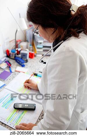Picture - Female doctor checks her diary to screen calls patients.. Fotosearch