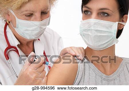 female doctorwith mask and red stethoscope vaccinating or giving an injection to young woman patient with mak too View Large Photo Image Stock Photograph - female doctorwith mask and red stethoscope vaccinating or giving an injection to young woman patient with mak too. Fotosearch