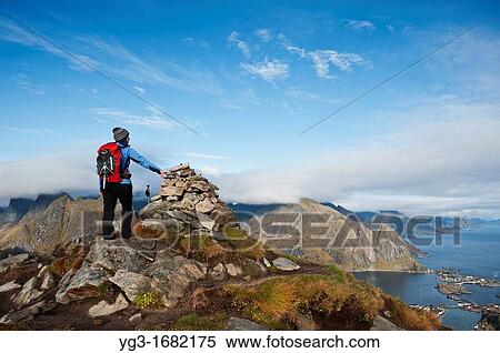 Female hiker enjoys spectacular view over mountains and fjords from Reinebringen, Lofoten islands, Norway View Large Photo Image Stock Photography - Female hiker enjoys spectacular view over mountains and fjords from Reinebringen, Lofoten islands, Norway. Fotosearch