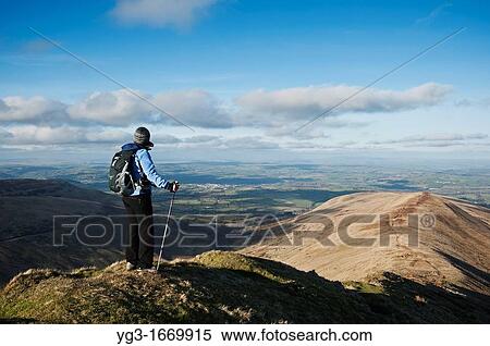 Stock Photography - Female hiker enjoys view from Fan Y Big looking towads Brecon, Brecon Beacons national park, Wales. Fotosearch