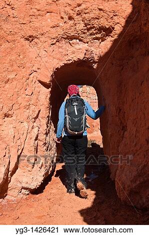 Stock Image - Female hiker enters tunnel on Queens Garden trail, Bryce Canyon national park, Utah, USA. Fotosearch