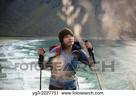 Stock Image - Female hiker hiking up trail with Kvalvika beach in background, Moskenesoy, Lofoten Islands, Norway.. Fotosearch
