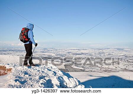 Stock Photo - Female hiker in winter looks out from summit of Corn Du, Brecon Beacons national park, Wales. Fotosearch