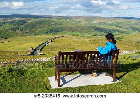 Stock Photography - Female hiker on seat overlooking Buttertubs pass in The Yorkshire Dales National Park. Yorkshire, England, UK.. Fotosearch